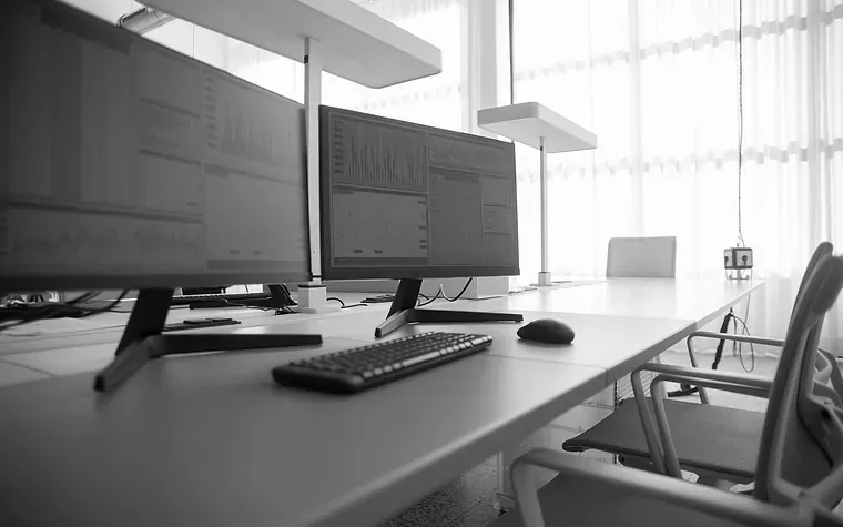 Empty desk with several monitors in a daylit office
