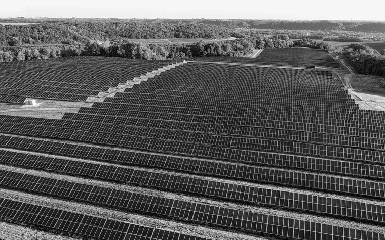 Aerial rows of solar panels across open farmland