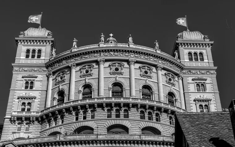 Domed facade of the Swiss Federal Palace beneath two Swiss flags