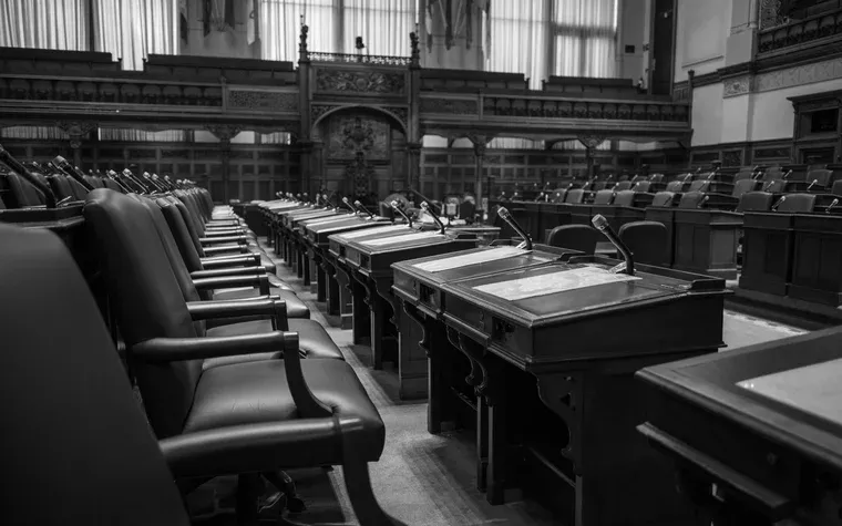 Empty benches and microphones in a legislative chamber
